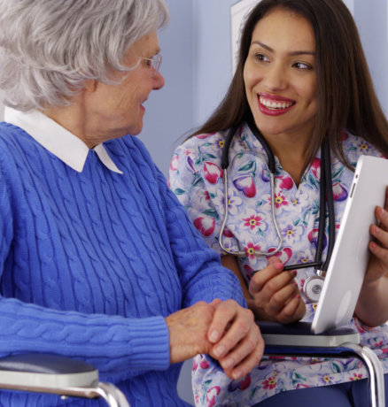 caregiver talking to elderly patient with tablet